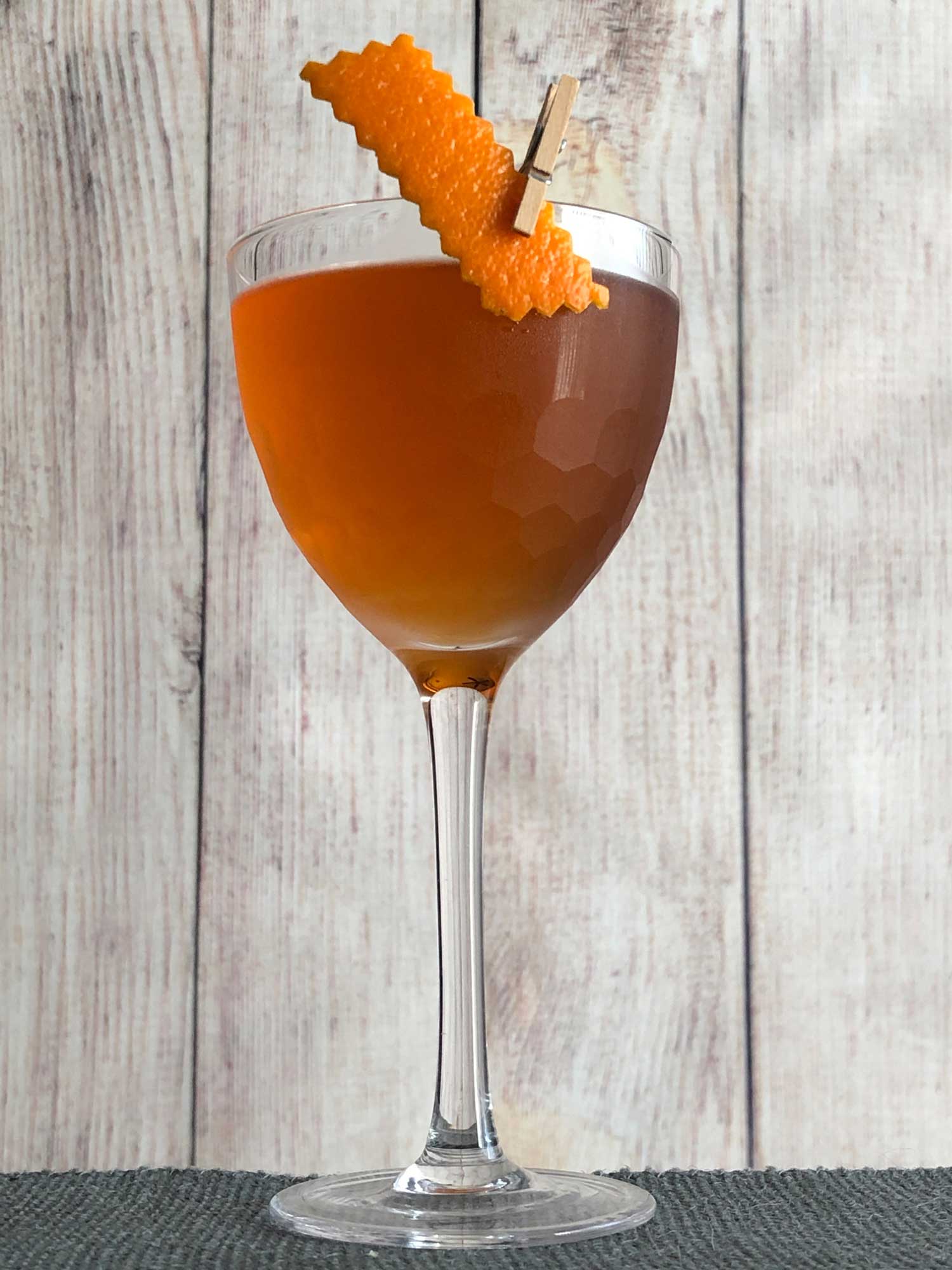 An example of the Overtime Cocktail, the mixed drink (cocktail), by based on the Coin Toss, Death & Co, New York City, featuring The Scarlet Ibis Trinidad Rum, Cocchi Vermouth di Torino ‘Storico’, Dolin Génépy le Chamois Liqueur, Bénédictine, and Peychaud’s Aromatic Cocktail Bitters; photo by Lee Edwards