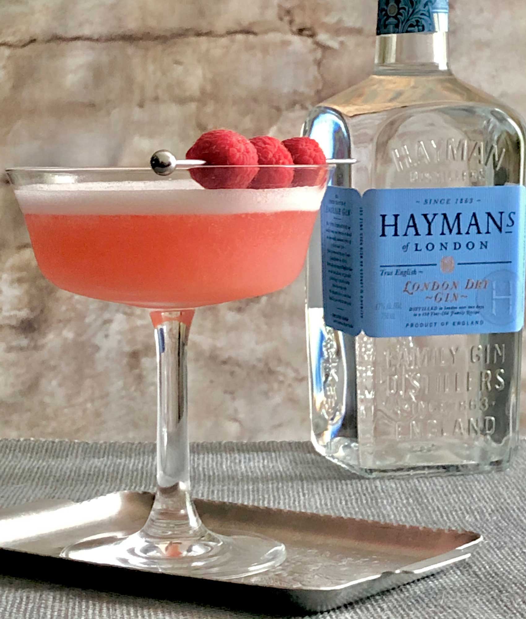 An example of the Clover Club, the mixed drink (cocktail), Adapted by Julie Reiner, NYC, featuring Hayman’s London Dry Gin, egg white, lemon juice, Dolin Dry Vermouth de Chambéry, and raspberry syrup; photo by Lee Edwards